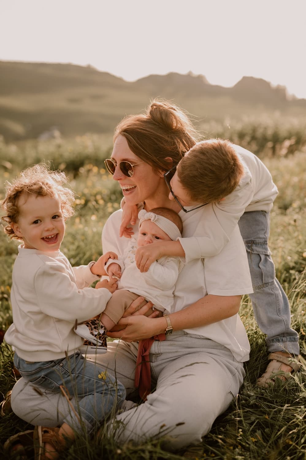 Julie avec ses trois enfants dans un champ au coucher du soleil